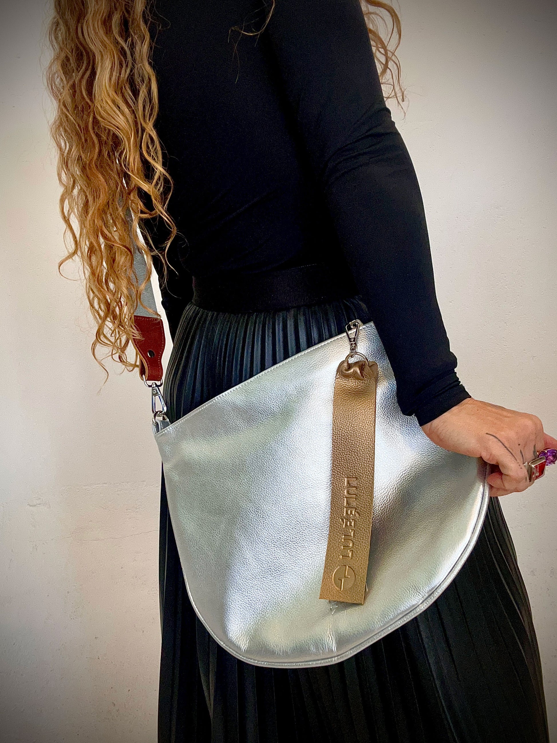 Arco Bag Silver — metallic silver leather crossbody bag with adjustable strap, worn by model | LULÉ LULÉ